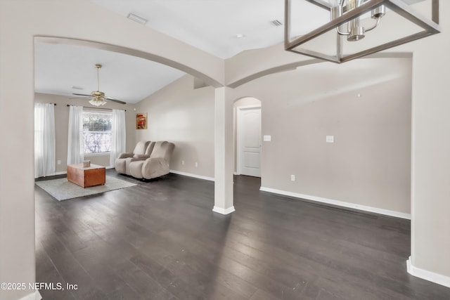 unfurnished living room featuring ceiling fan, arched walkways, wood finished floors, and vaulted ceiling