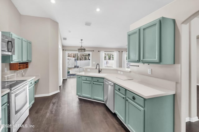 kitchen with dark wood-type flooring, a sink, appliances with stainless steel finishes, a peninsula, and light countertops