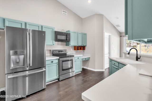 kitchen featuring visible vents, a sink, appliances with stainless steel finishes, light countertops, and vaulted ceiling