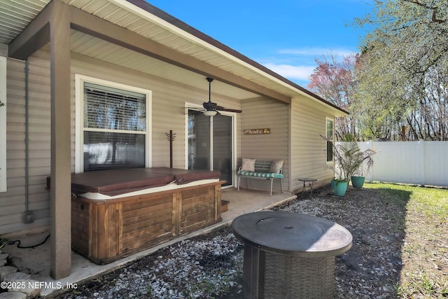 view of patio / terrace with a hot tub, ceiling fan, and fence