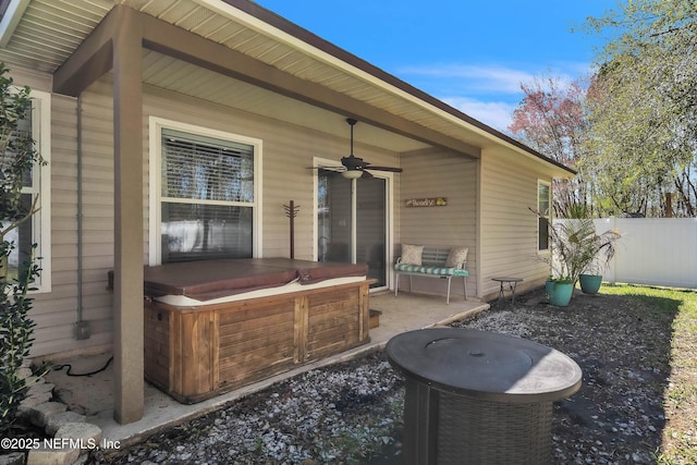 view of patio / terrace with a hot tub, a ceiling fan, and fence