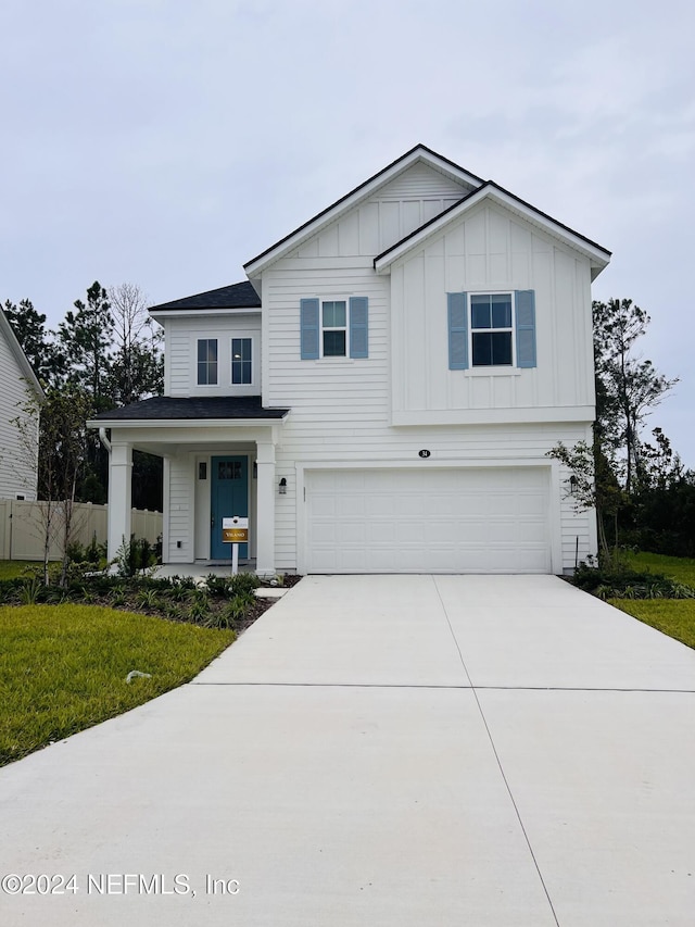 view of front facade featuring an attached garage, fence, concrete driveway, board and batten siding, and a front yard