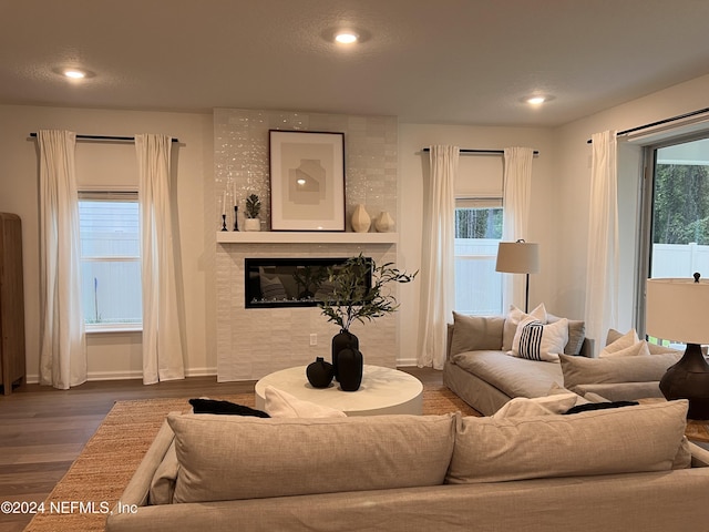 living room featuring baseboards, plenty of natural light, a tiled fireplace, and wood finished floors