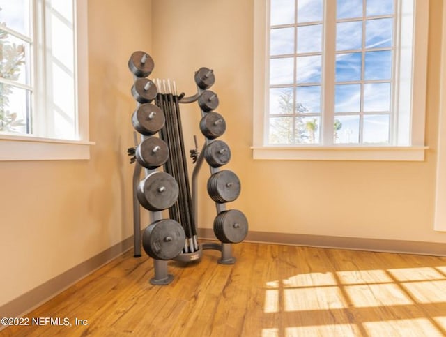 workout area with baseboards and wood finished floors