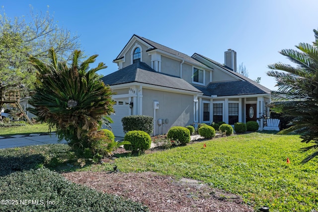 view of front of property with a chimney, a front yard, an attached garage, and stucco siding