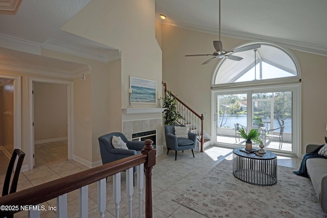 living room with ceiling fan, light tile patterned flooring, ornamental molding, and a tile fireplace