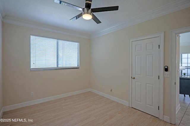 unfurnished room featuring ceiling fan, light wood finished floors, a wealth of natural light, and crown molding