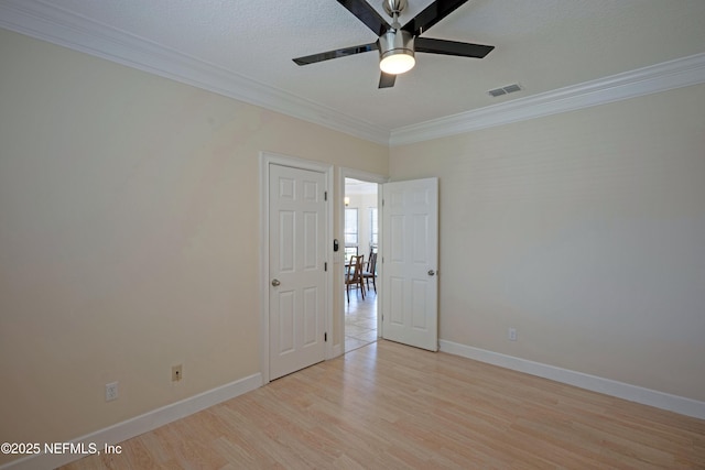 unfurnished room featuring baseboards, crown molding, visible vents, and wood finished floors