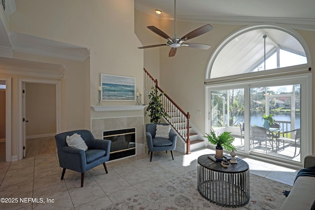 living area with light tile patterned floors, high vaulted ceiling, a fireplace, stairs, and ornamental molding