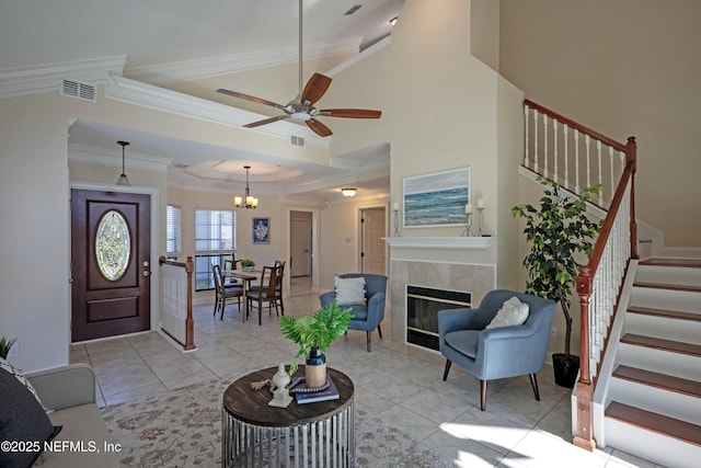 foyer entrance with ornamental molding, a tile fireplace, visible vents, and stairway