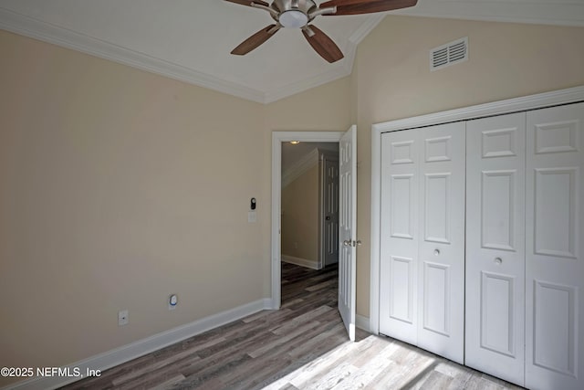 unfurnished bedroom featuring vaulted ceiling, visible vents, crown molding, and wood finished floors