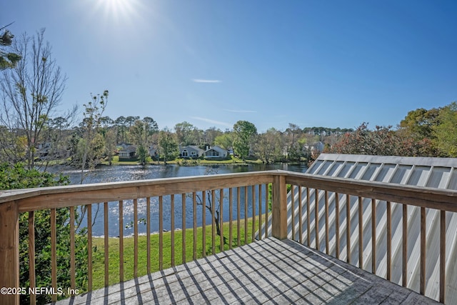 wooden deck featuring a water view and a lawn