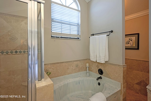 full bathroom with wainscoting, a garden tub, crown molding, a shower stall, and tile walls