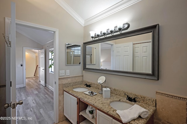 bathroom featuring vaulted ceiling, ornamental molding, wood finished floors, and a sink