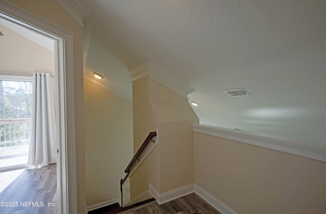 staircase featuring lofted ceiling, baseboards, visible vents, and wood finished floors