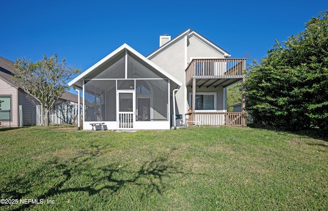 back of property featuring a yard, a chimney, a sunroom, and stucco siding