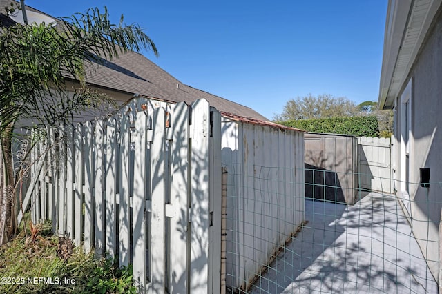 view of property exterior with a shingled roof, a gate, and fence