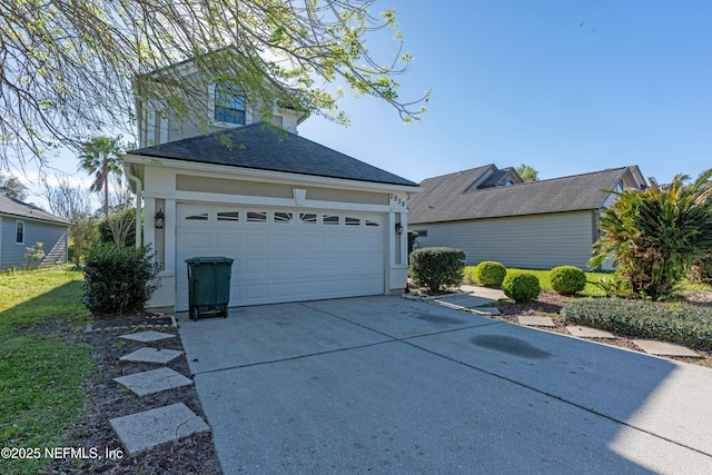 view of front facade with a shingled roof, concrete driveway, and stucco siding