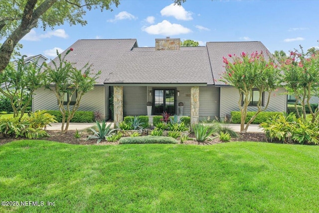 view of front of home featuring a shingled roof, a front yard, and a chimney