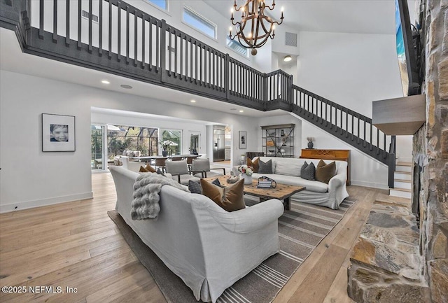 living room featuring visible vents, baseboards, a chandelier, stairs, and hardwood / wood-style flooring