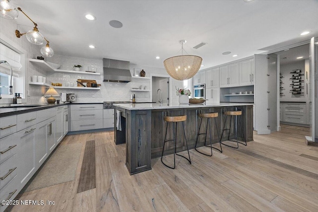 kitchen featuring visible vents, oven, light wood-style flooring, wall chimney exhaust hood, and open shelves