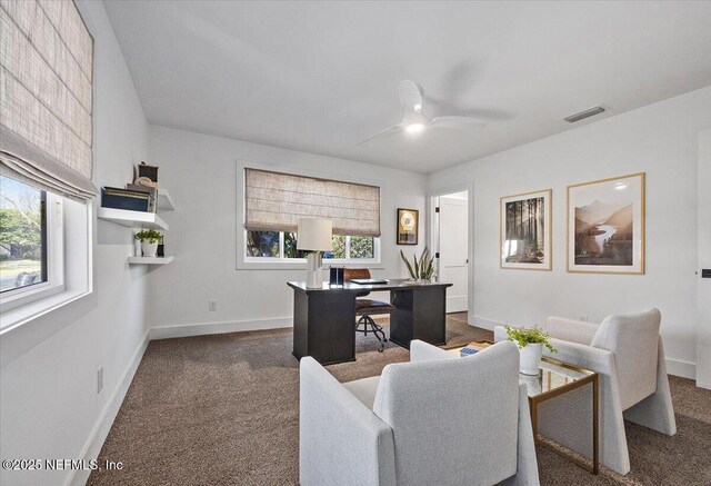 home office with visible vents, dark carpet, baseboards, and a ceiling fan