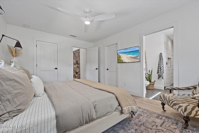 bedroom featuring wood finished floors, visible vents, baseboards, ceiling fan, and ensuite bathroom