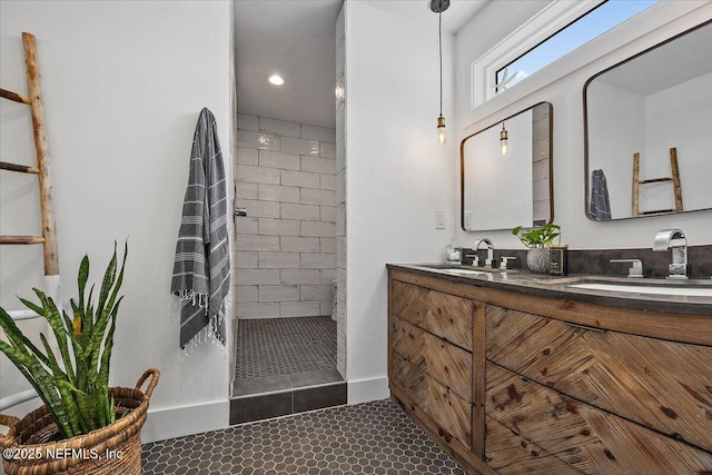 bathroom featuring a tile shower, tile patterned floors, double vanity, and a sink