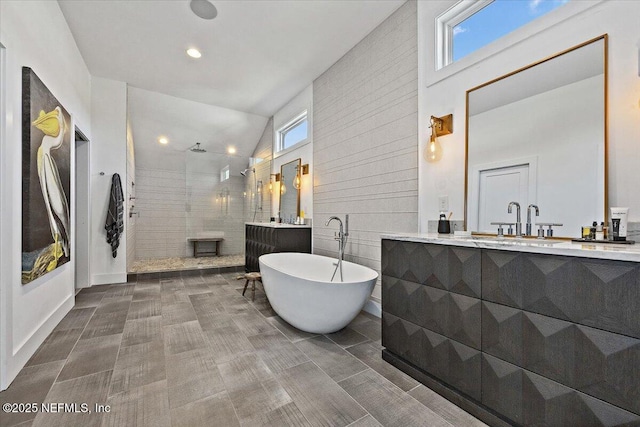 bathroom with a freestanding bath, vaulted ceiling, vanity, and a walk in shower