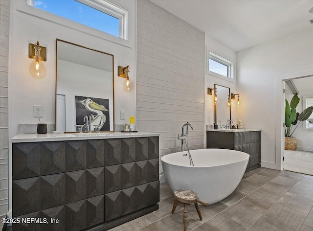 bathroom with a sink, two vanities, and a freestanding tub