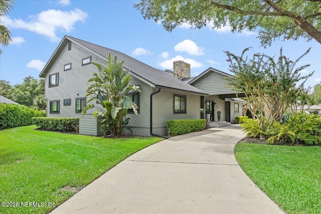 view of front of home with a chimney, concrete driveway, and a front yard