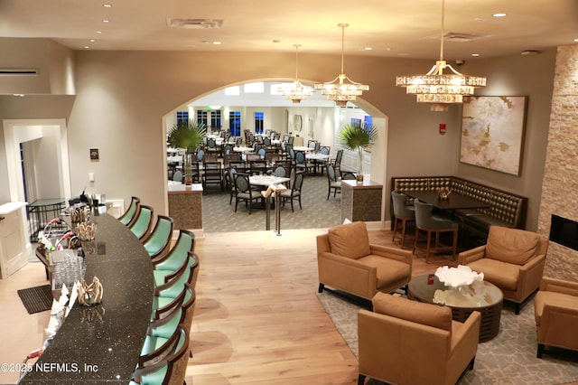 living area featuring recessed lighting, arched walkways, an inviting chandelier, and wood finished floors