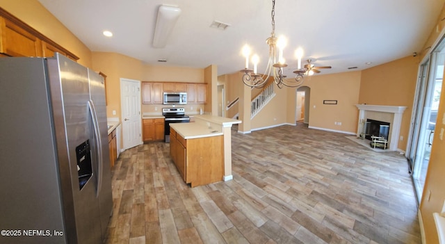 kitchen featuring a premium fireplace, appliances with stainless steel finishes, open floor plan, light countertops, and light wood-type flooring