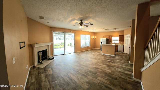 unfurnished living room featuring a textured ceiling, stairway, dark wood finished floors, and visible vents