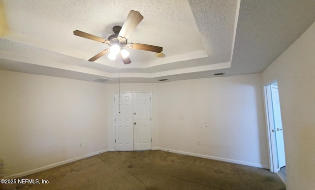 carpeted spare room with visible vents, baseboards, a raised ceiling, ceiling fan, and a textured ceiling