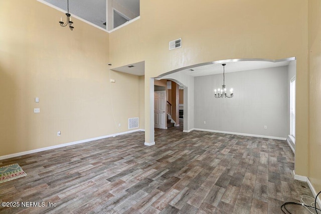 3925 Leatherwood Dr, Orange Park, FL 32065 - unfurnished living room with arched walkways, wood finished floors, a chandelier, baseboards, and a towering ceiling