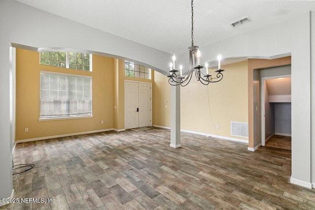3925 Leatherwood Dr, Orange Park, FL 32065 - unfurnished dining area featuring a chandelier, arched walkways, wood finished floors, baseboards, and a textured ceiling