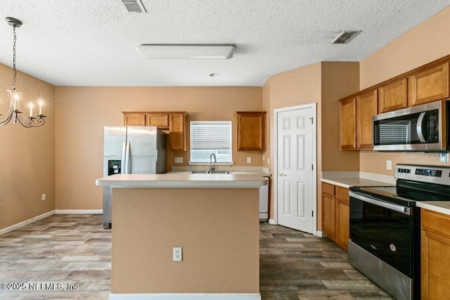 3925 Leatherwood Dr, Orange Park, FL 32065 - kitchen with stainless steel appliances, dark wood finished floors, brown cabinetry, and a textured ceiling