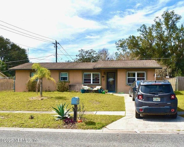 ranch-style home with a front yard, fence, and stucco siding