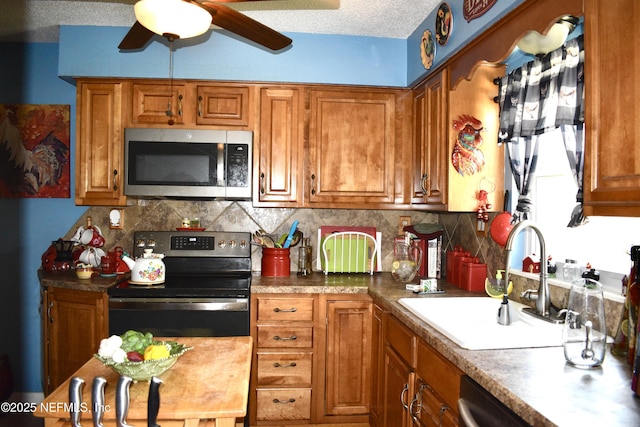 kitchen featuring appliances with stainless steel finishes, brown cabinetry, a sink, and backsplash