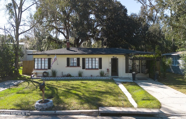 ranch-style home with driveway, a chimney, a front lawn, a carport, and stucco siding