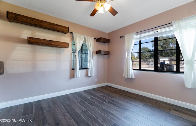 empty room with dark wood-style flooring, ceiling fan, and baseboards