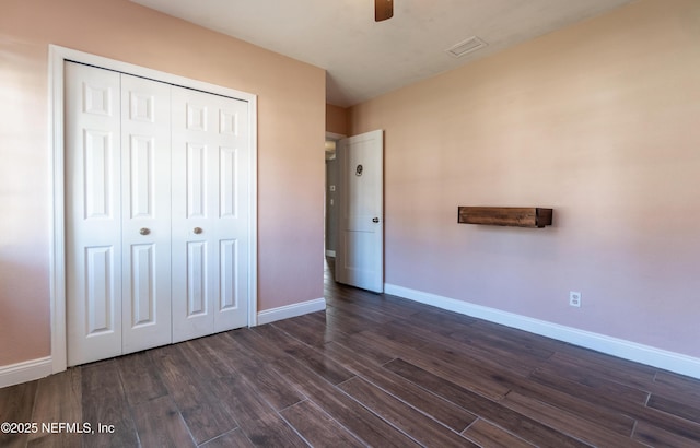 unfurnished bedroom with ceiling fan, visible vents, baseboards, a closet, and dark wood finished floors