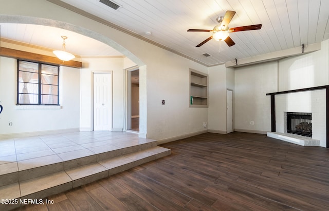 unfurnished living room featuring arched walkways, visible vents, wood ceiling, a brick fireplace, and wood finished floors