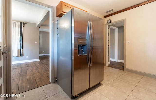 kitchen featuring light tile patterned floors, baseboards, visible vents, and stainless steel fridge with ice dispenser