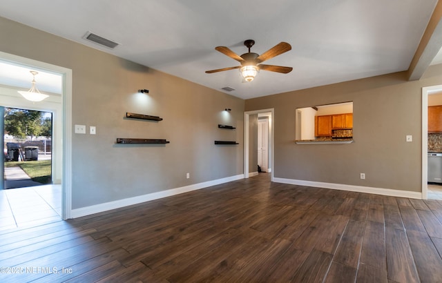 unfurnished living room featuring dark wood-type flooring, visible vents, baseboards, and a ceiling fan