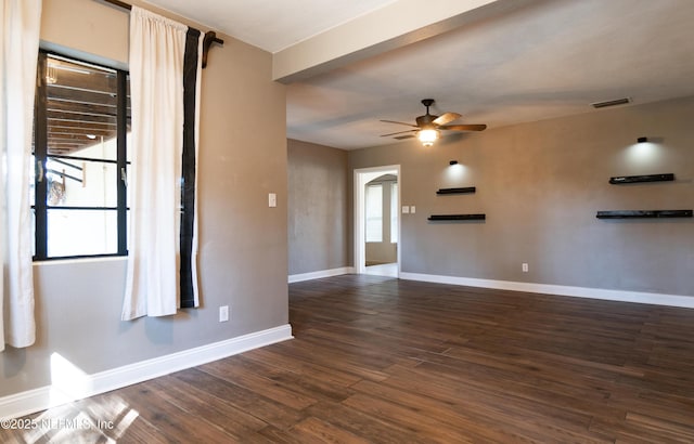 unfurnished room with a ceiling fan, dark wood-style flooring, visible vents, and baseboards