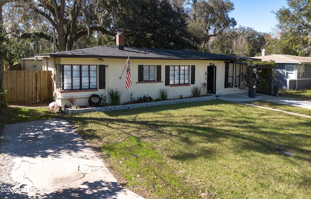 view of front of house featuring stucco siding, a chimney, fence, and a front yard