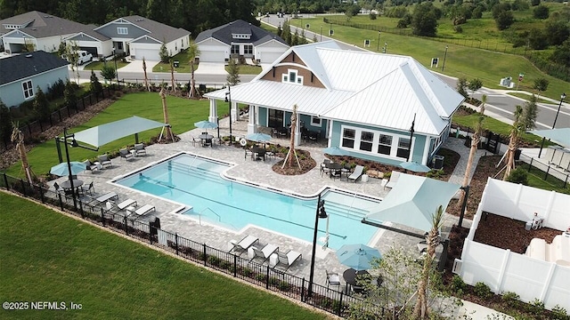 community pool with a patio, a lawn, and fence