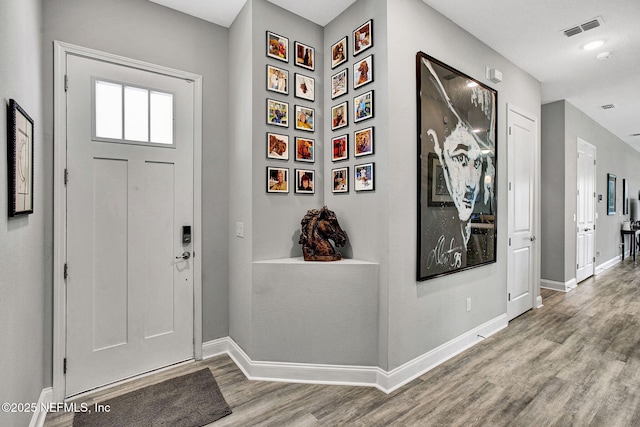 entrance foyer with wood finished floors, visible vents, and baseboards